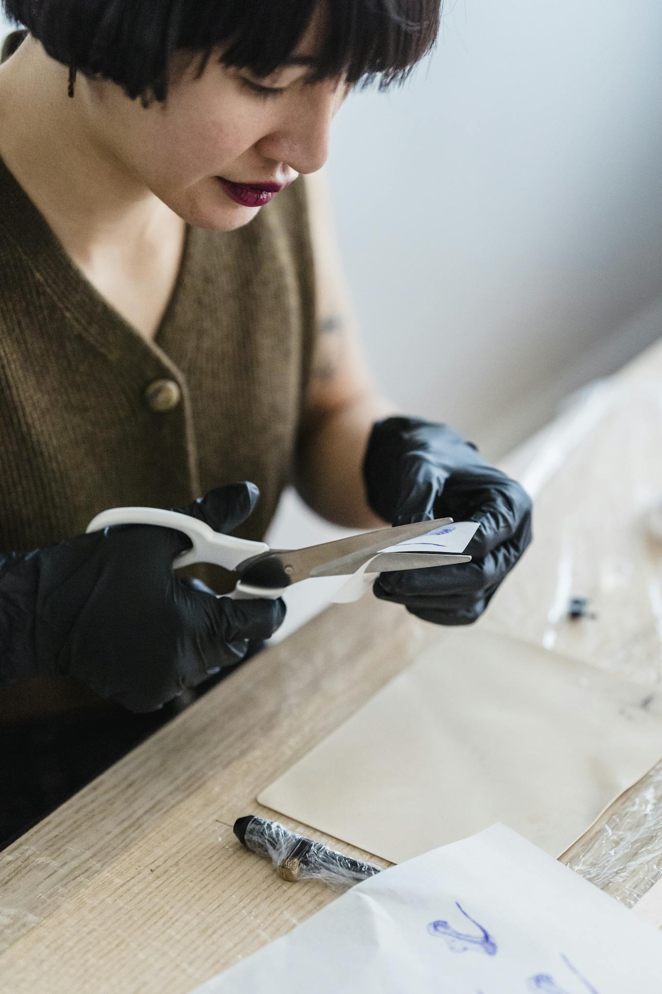 Woman with black gloves cuts paper with scissors, focused and artistic.